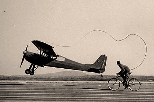 A bicyclist tethered to a propeller plane.